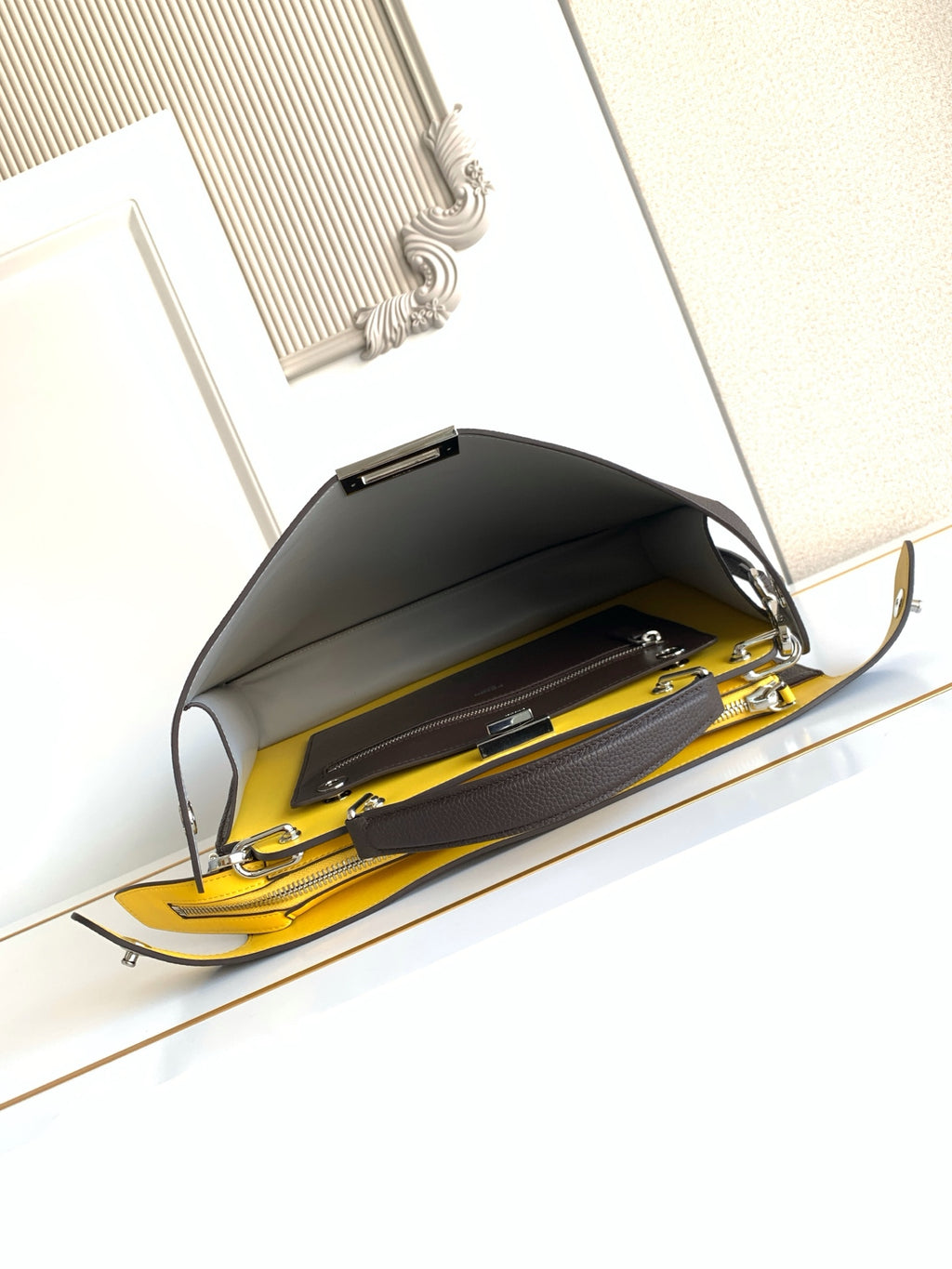 Fendi dark crossbody bag open, showing yellow interior and zippered pockets