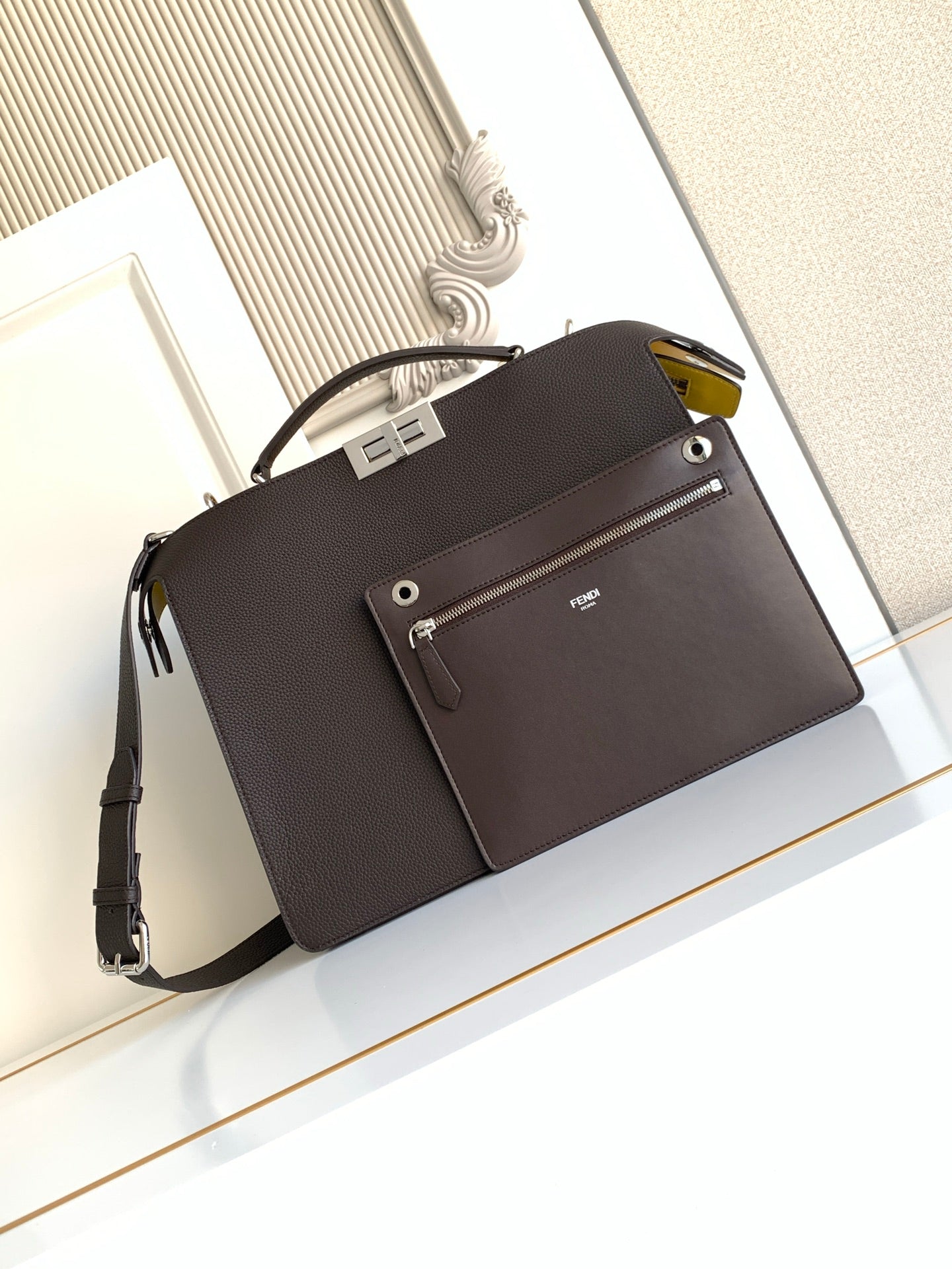 Fendi dark crossbody bag with front flap, belt-style strap, and small logo plaque