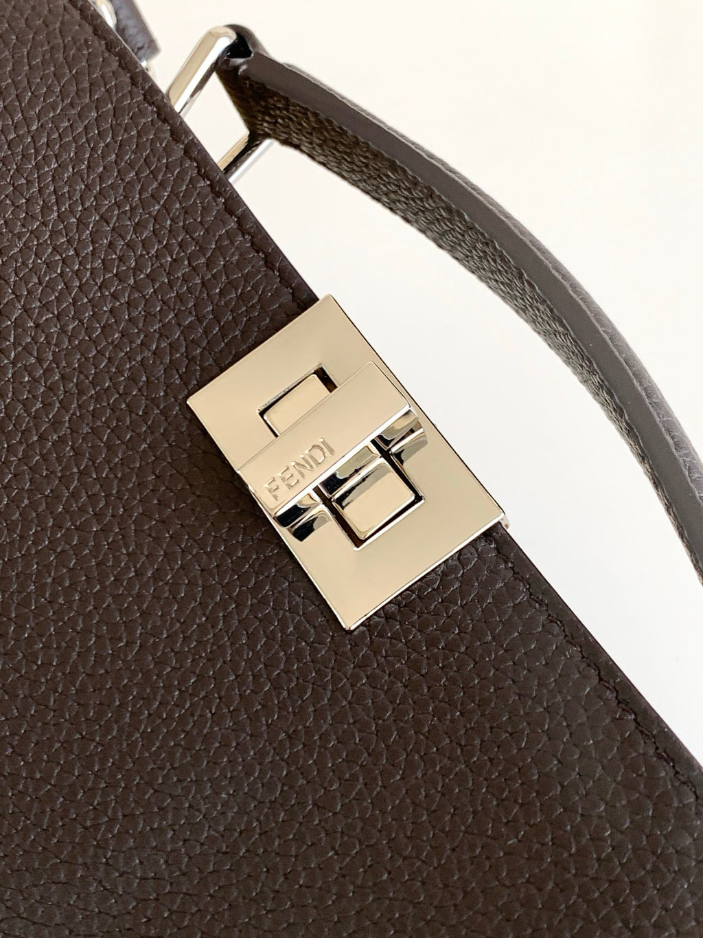 Fendi bag strap clasp close-up with gold-toned metal buckle and engraved logo plate