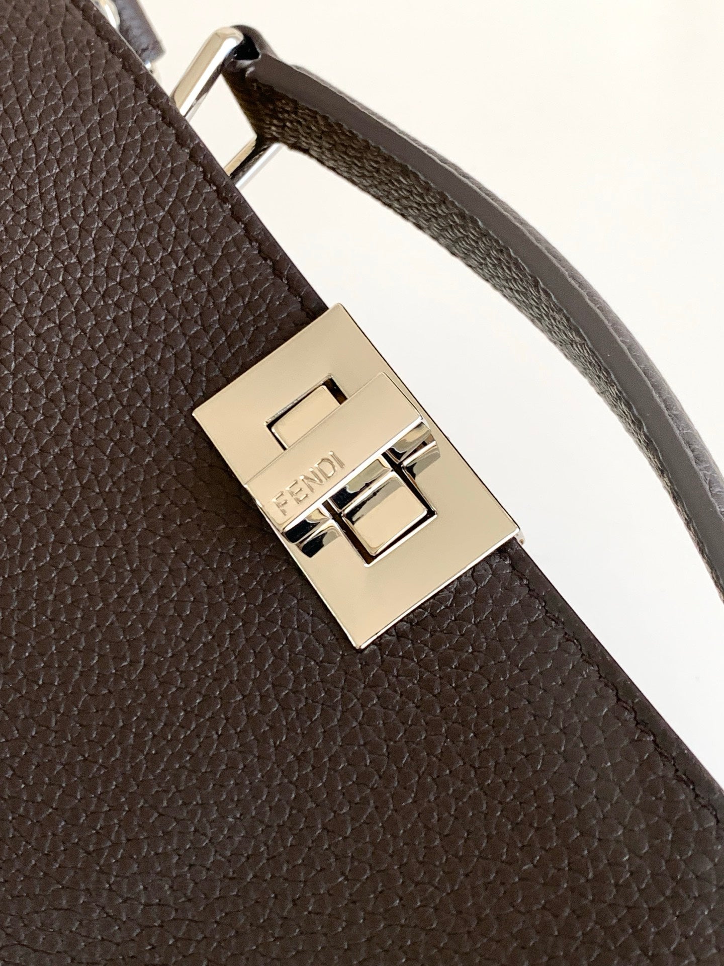 Fendi bag strap clasp close-up with gold-toned metal buckle and engraved logo plate