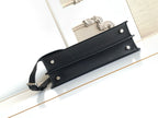 Black crossbody bag with top handle strap and two silver button accents.