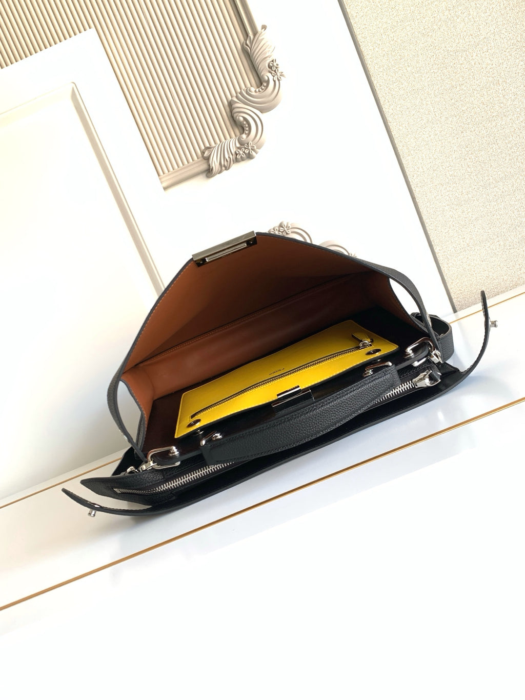 Open bag showing yellow lining and brown interior with zipped compartments.