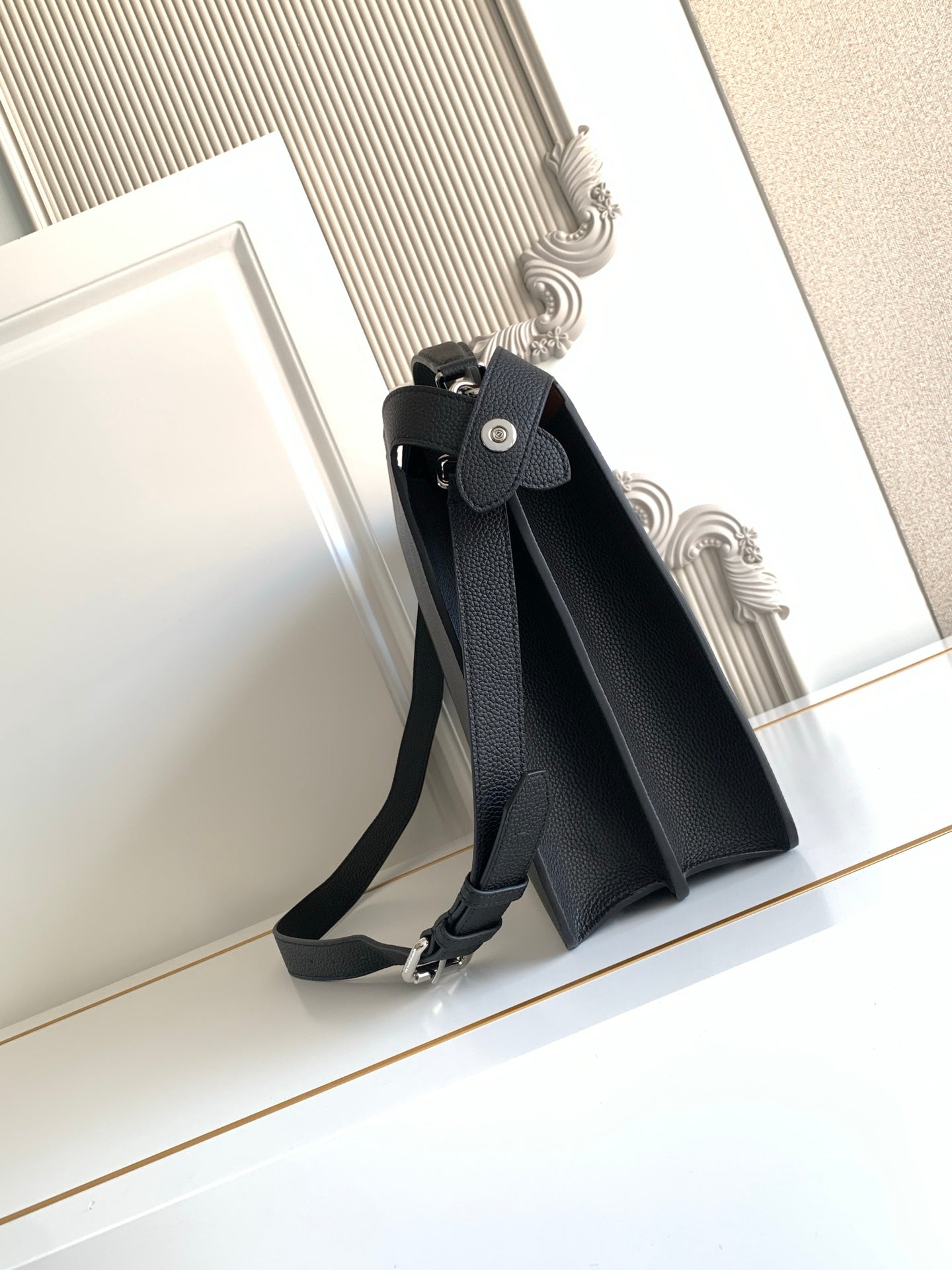 Black crossbody bag with adjustable shoulder strap and metal buckle detail.