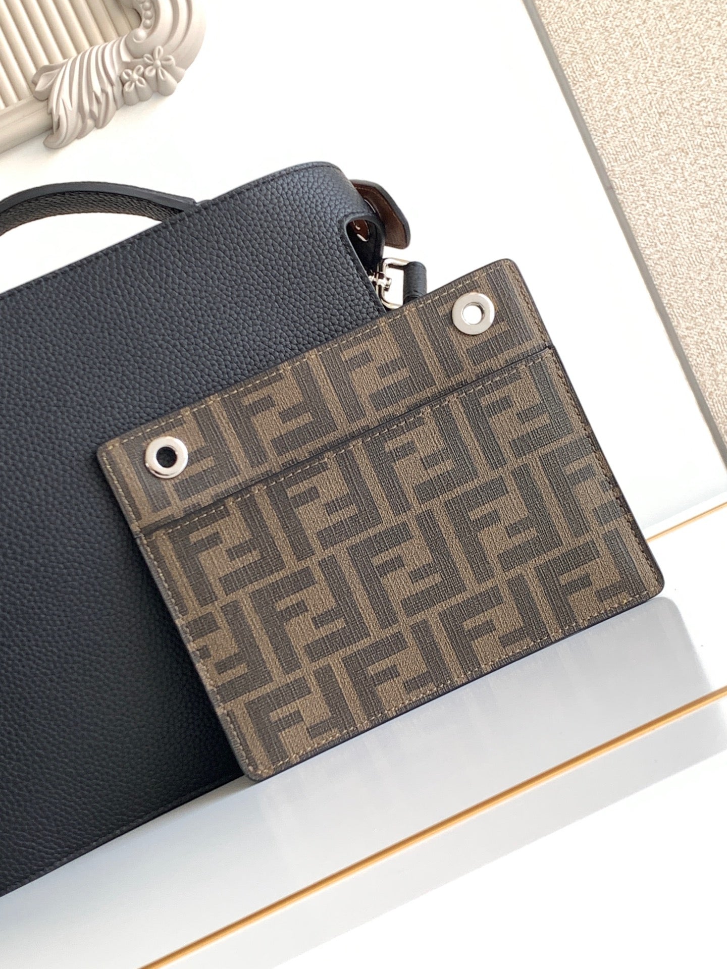 Black leather shoulder bag with brown logo-print front panel and snap closure