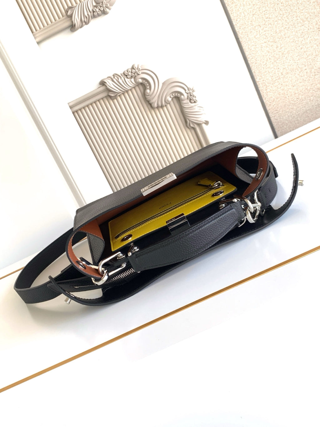 Black leather shoulder bag open to yellow interior with zip pocket