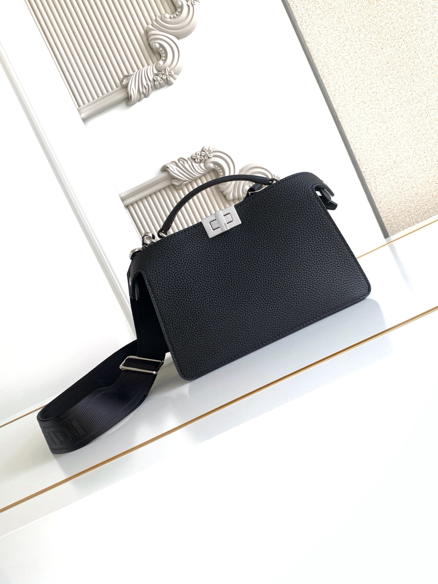 Black pebbled leather handbag with top handle and crossbody strap