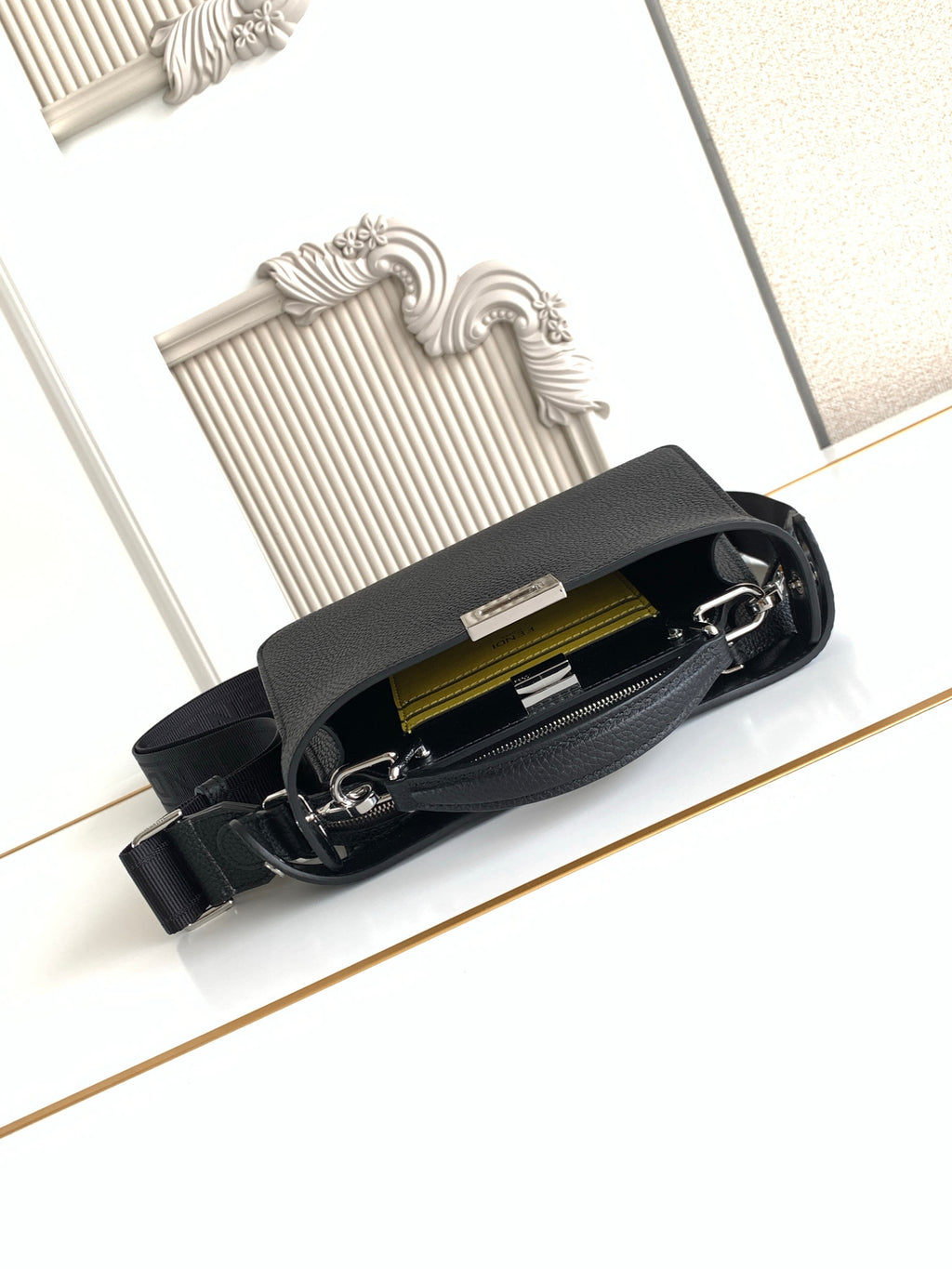 Black pebbled leather bag open to show interior pocket and zipper
