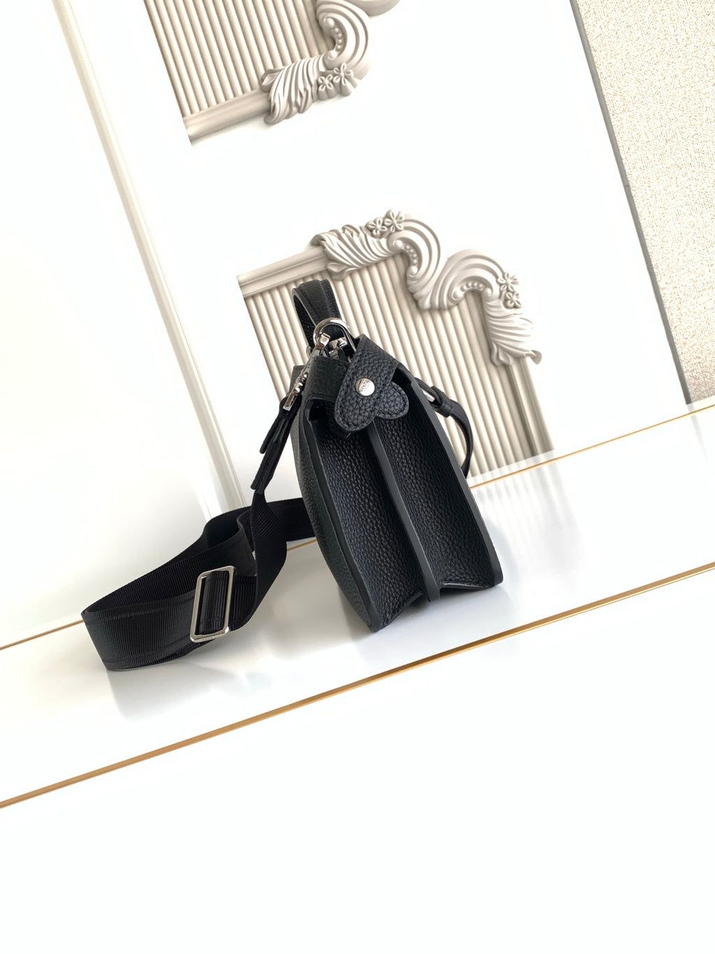 Black pebbled leather mini bag with structured top and crossbody strap