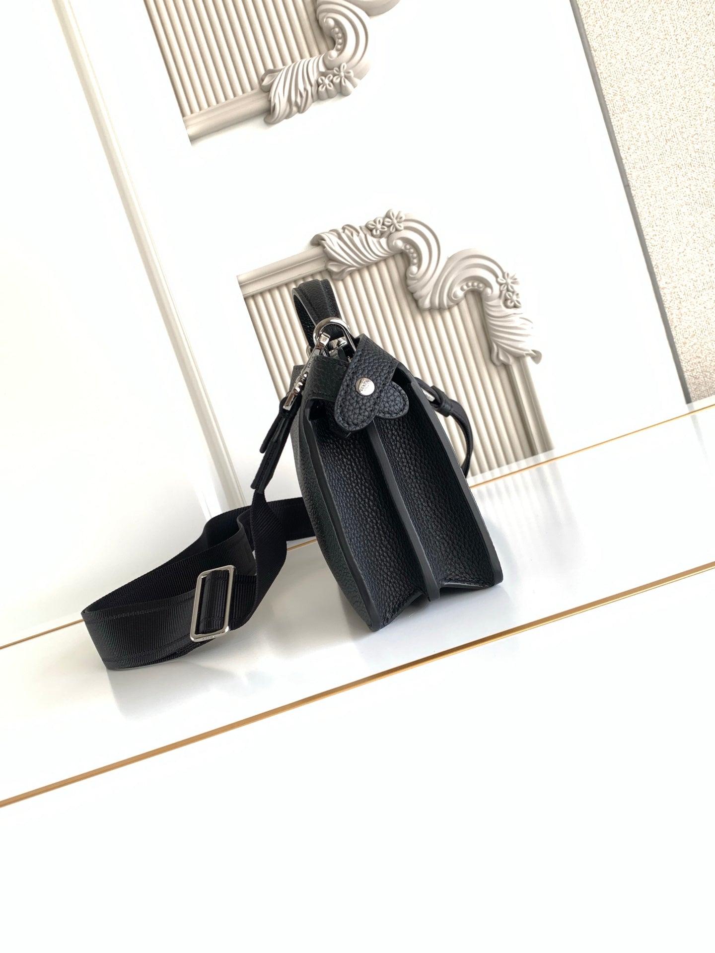 Black pebbled leather mini bag with structured top and crossbody strap