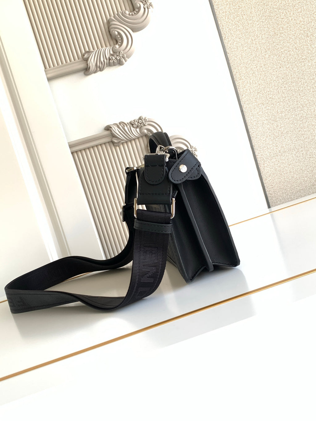Black Fendi crossbody bag shown from back with strap and top zip closure