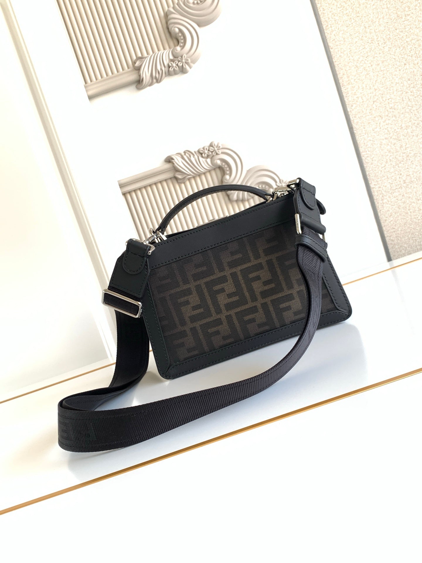 Black Fendi crossbody bag with adjustable web shoulder strap and gold-tone hardware