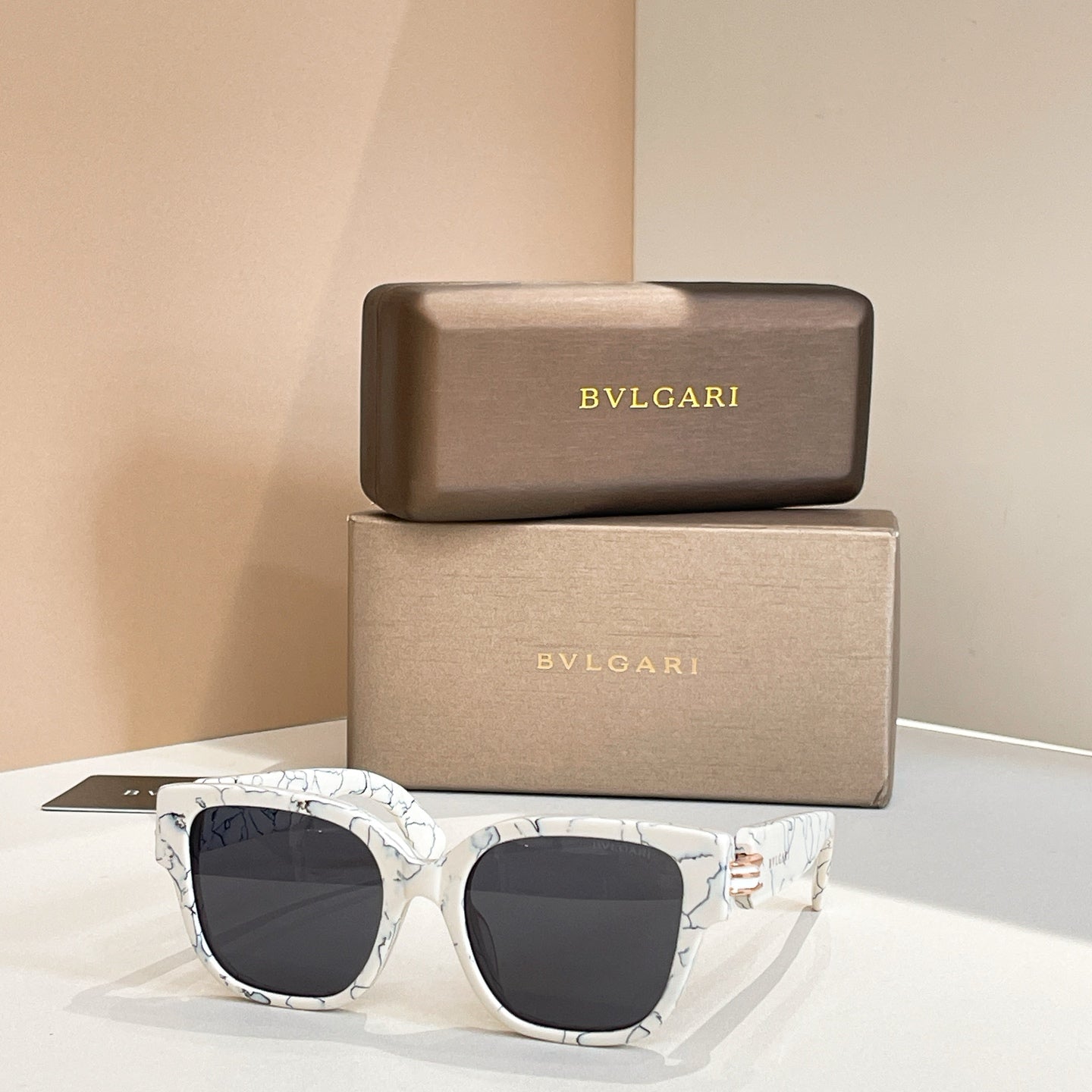 White marbled sunglasses with square lenses and dark tinted lenses, metal hinge detail.