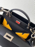 Black leather Fendi bag with yellow logo panels and silver-tone hardware, close-up