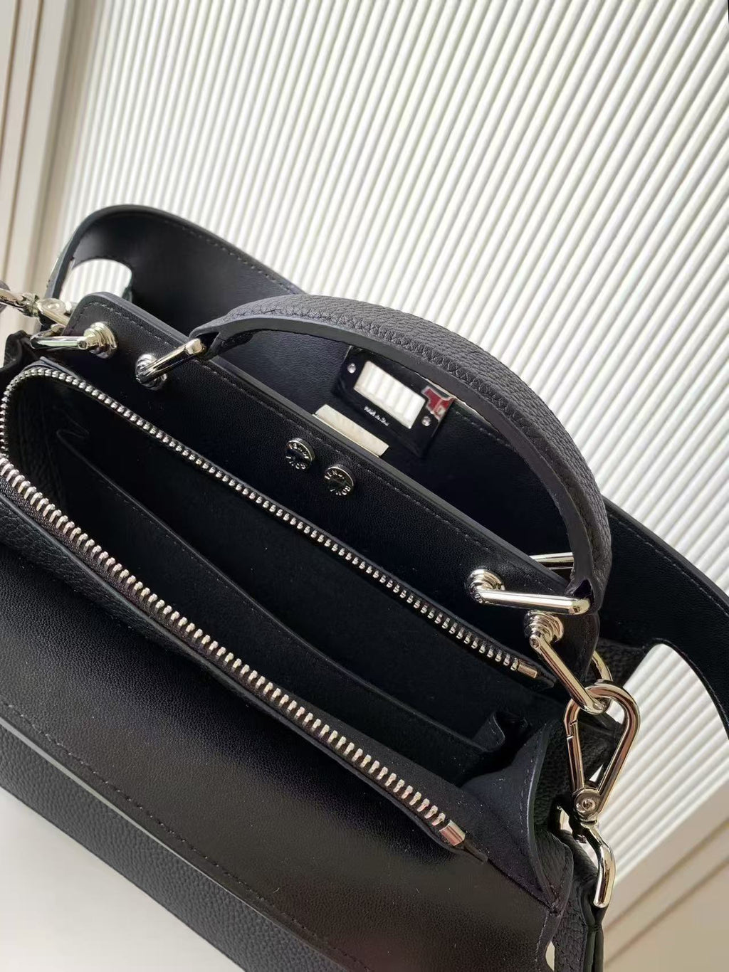 Black leather Fendi bag interior view with zipper pocket and metal rings, close-up