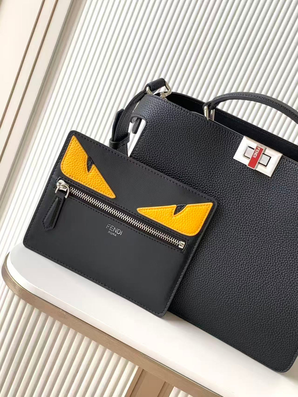 Black leather Fendi handbag with yellow triangular logo pockets and front zipper, angled