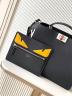 Black leather Fendi handbag with yellow triangular logo pockets and front zipper, angled