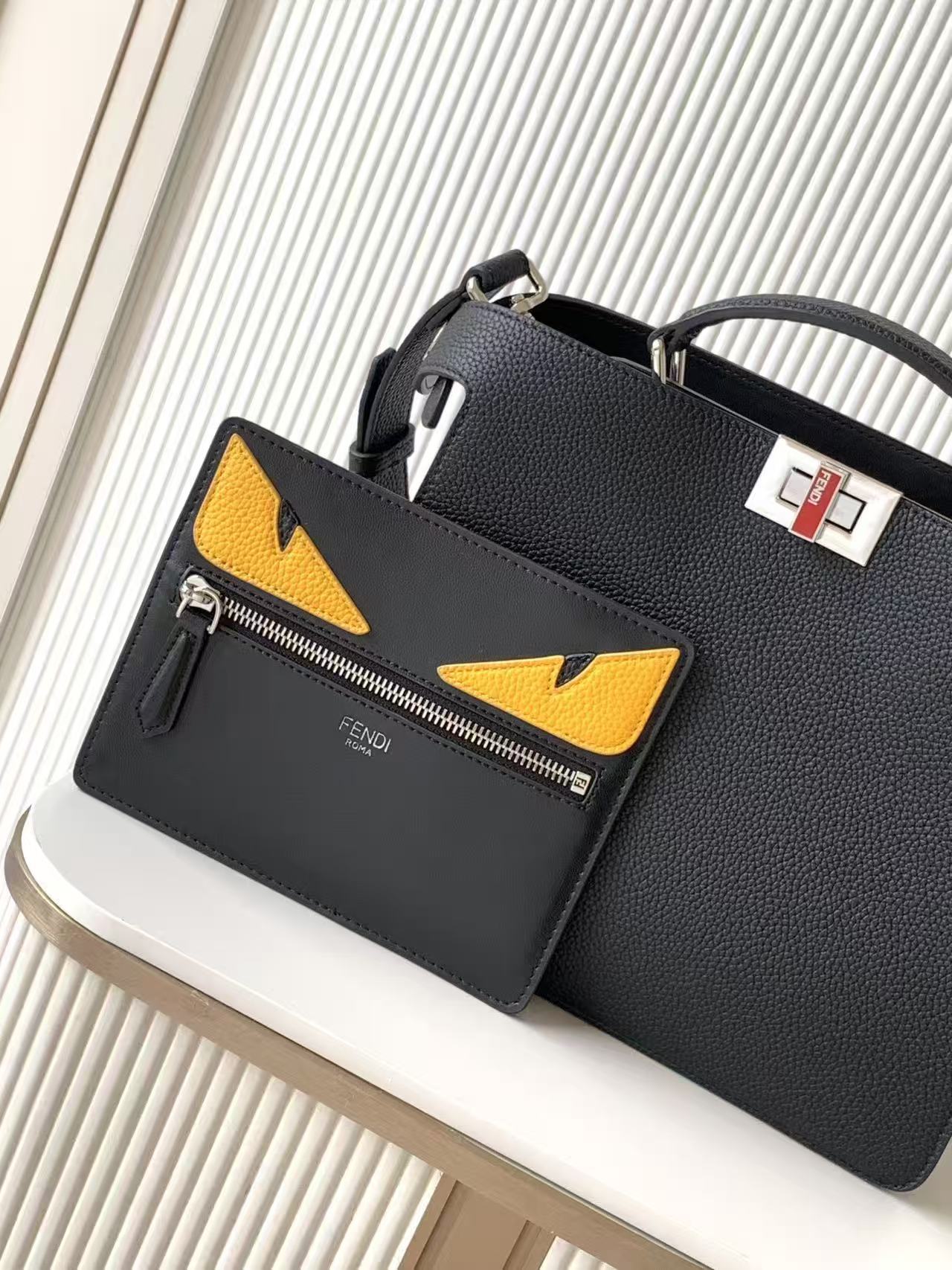 Black leather Fendi handbag with yellow triangular logo pockets and front zipper, angled