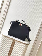 Black leather Fendi handbag with top handle and crossbody strap, front logo plaque