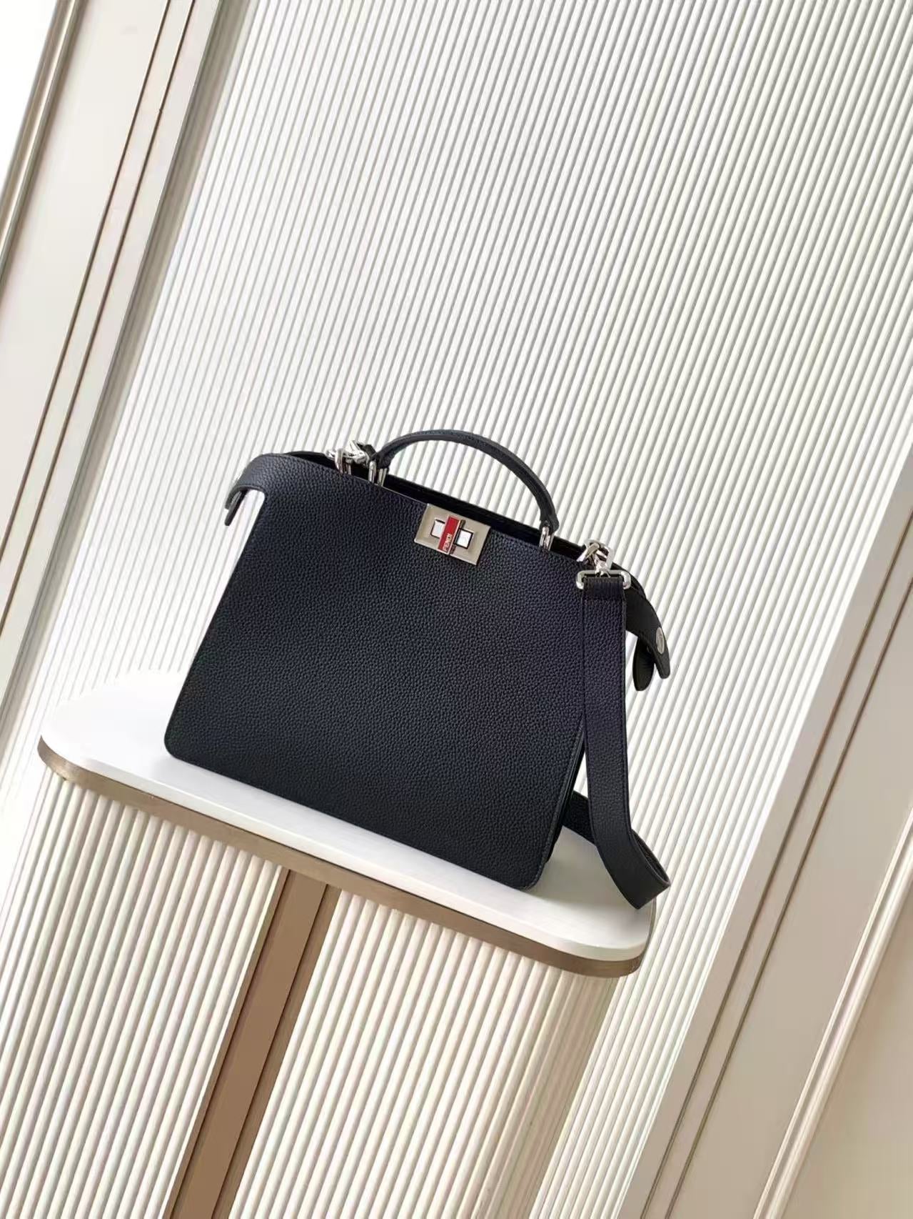 Black leather Fendi handbag with top handle and crossbody strap, front logo plaque