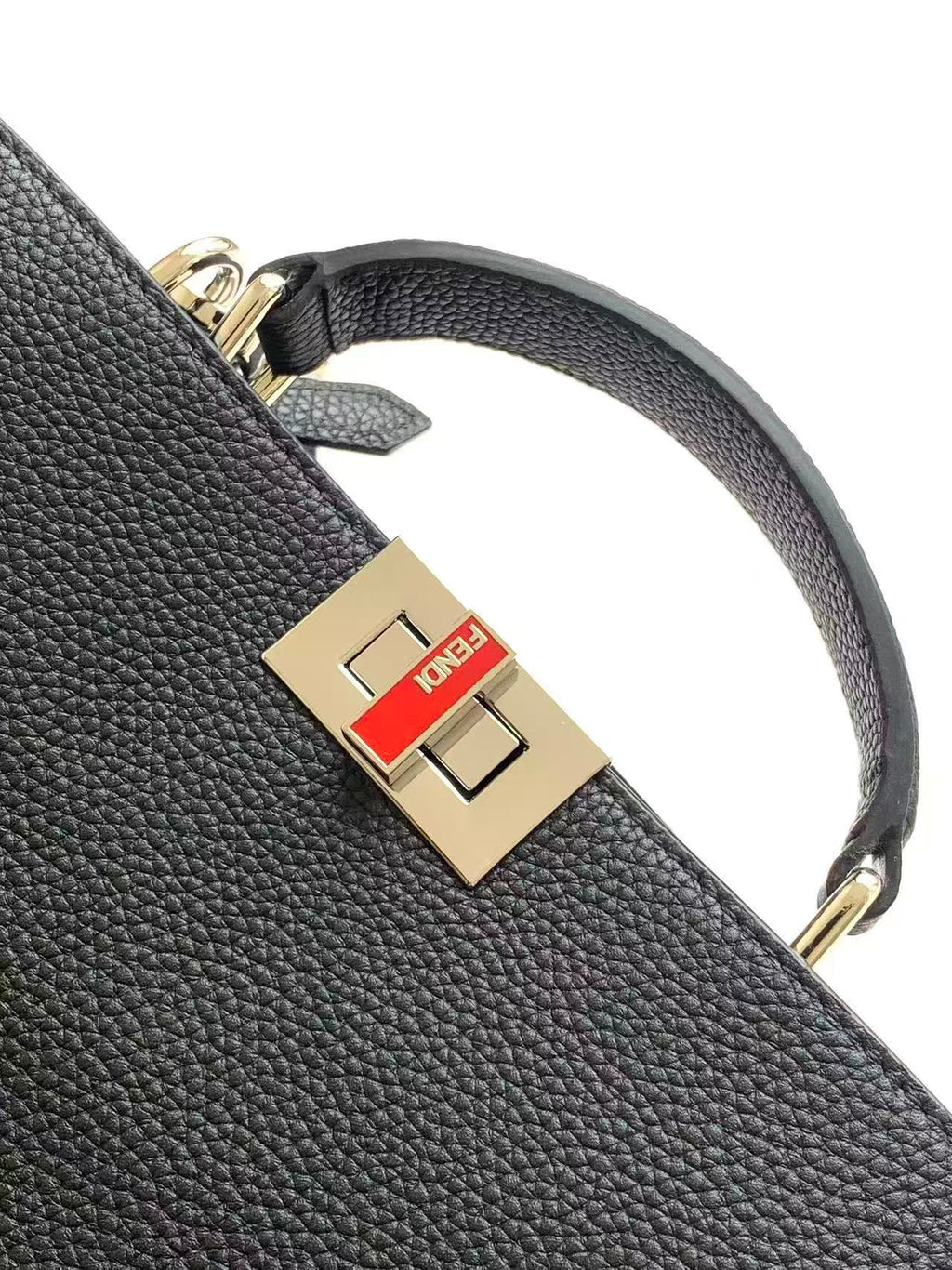 Black leather Fendi strap with gold square logo buckle, close-up