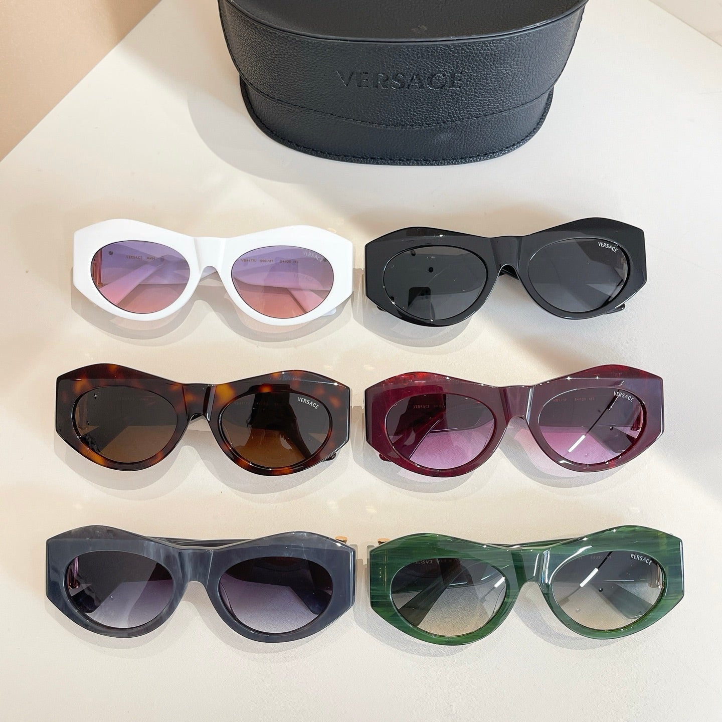 Six Versace sunglasses with assorted frames and lenses, beside black case