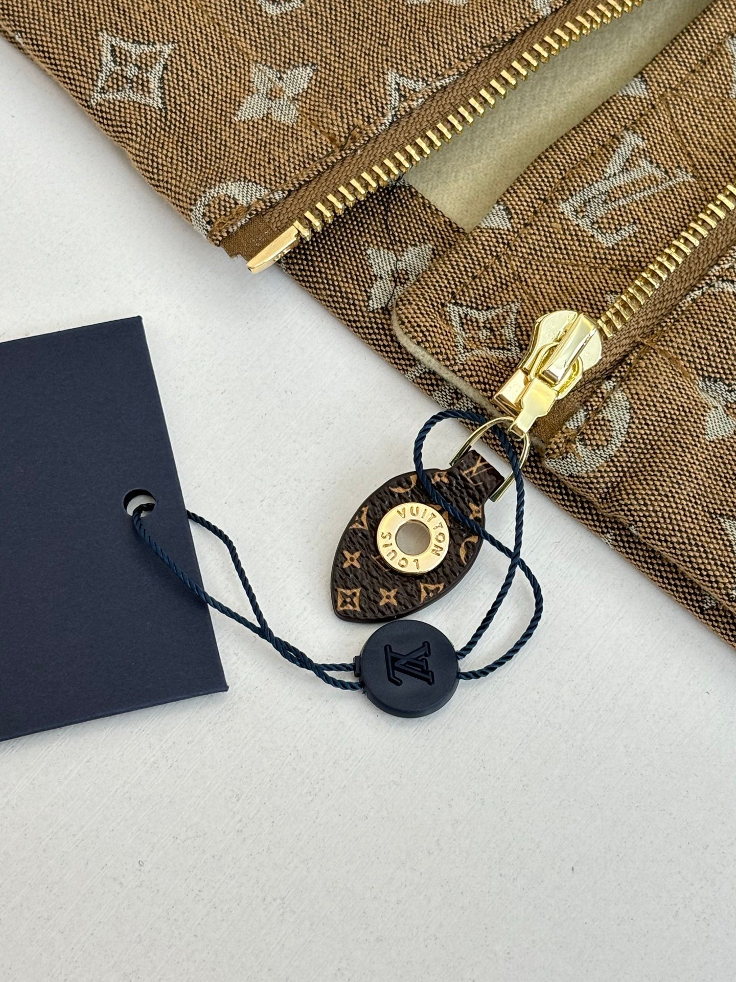 Louis Vuitton jacket accessories: gold zipper pull and round key charm on tags