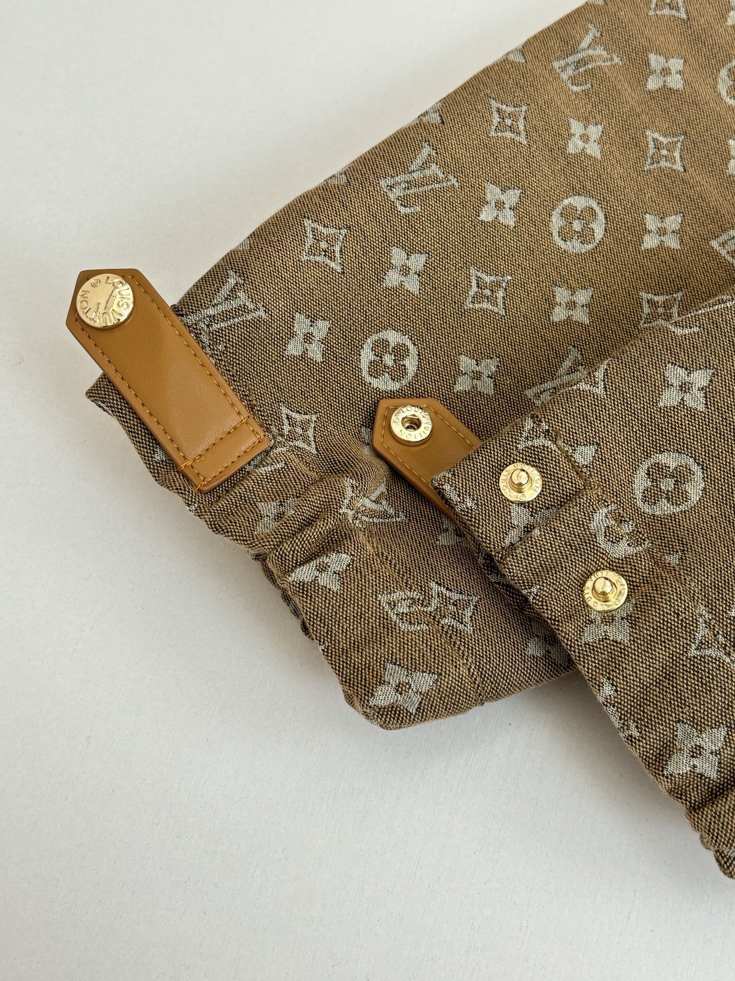 Louis Vuitton monogram jacket cuff detail with tan leather tabs and gold buttons