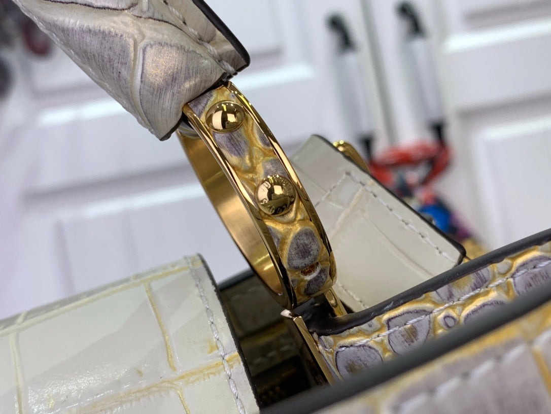 Louis Vuitton strap attachment with gold-tone buckle on white croc-embossed bag