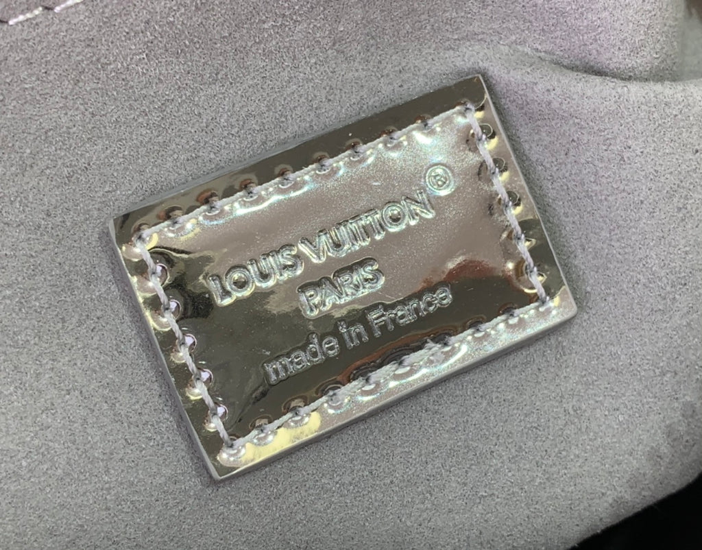 Silver Louis Vuitton handbag label patch with embossed text and rivet edges