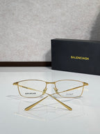 Balenciaga eyeglasses with clear lenses and gold metal frames, folded view.