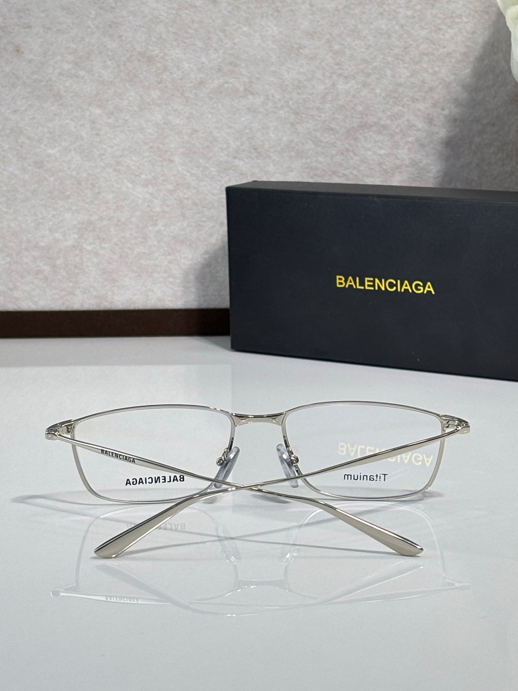 Balenciaga eyeglasses with clear lenses and silver metal frames on display.