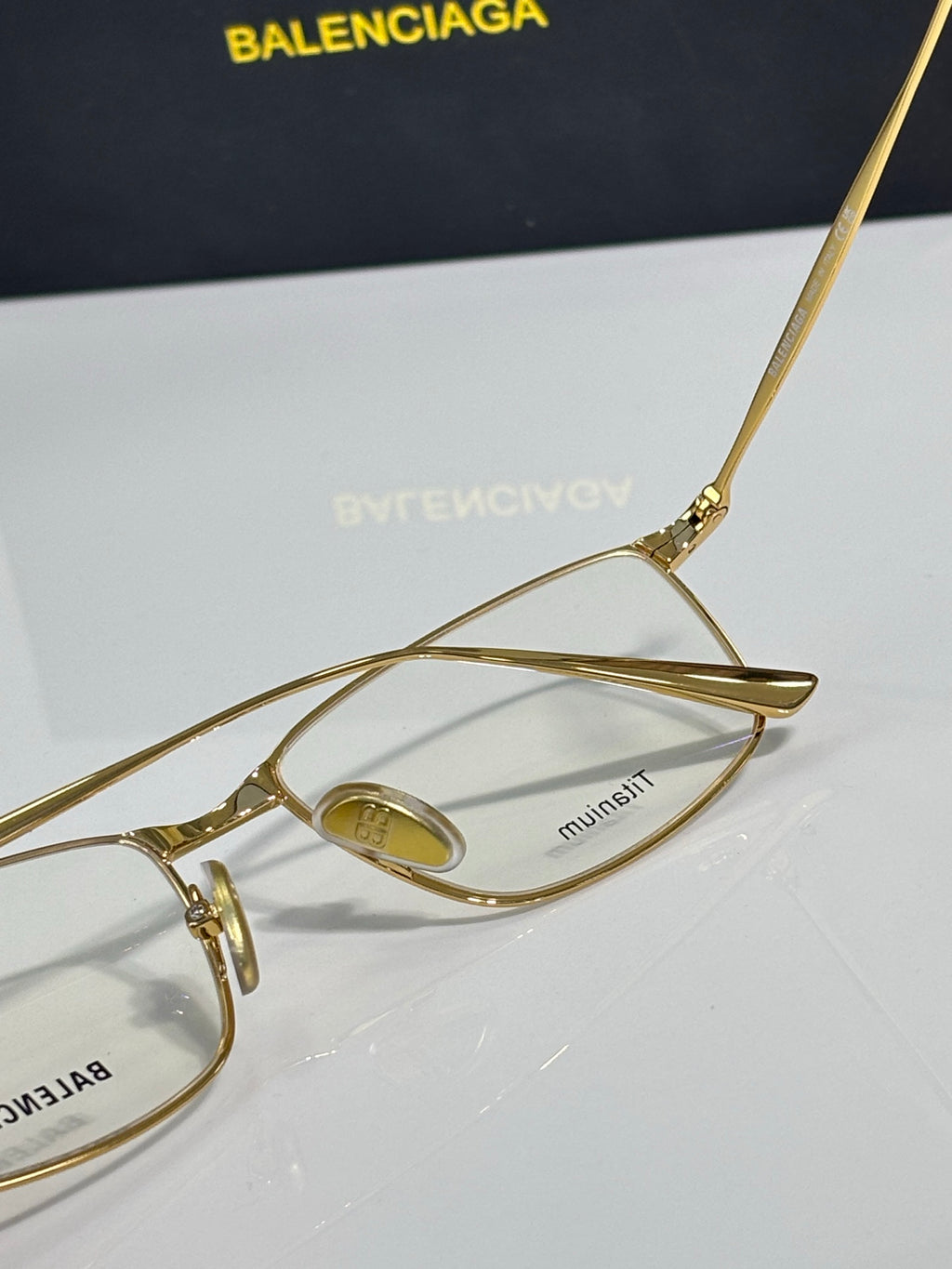 Balenciaga eyeglasses close-up with gold metal frame and tinted lens center.