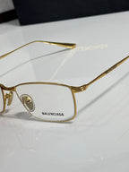 Balenciaga eyeglasses close-up with gold metal frame and clear lenses.