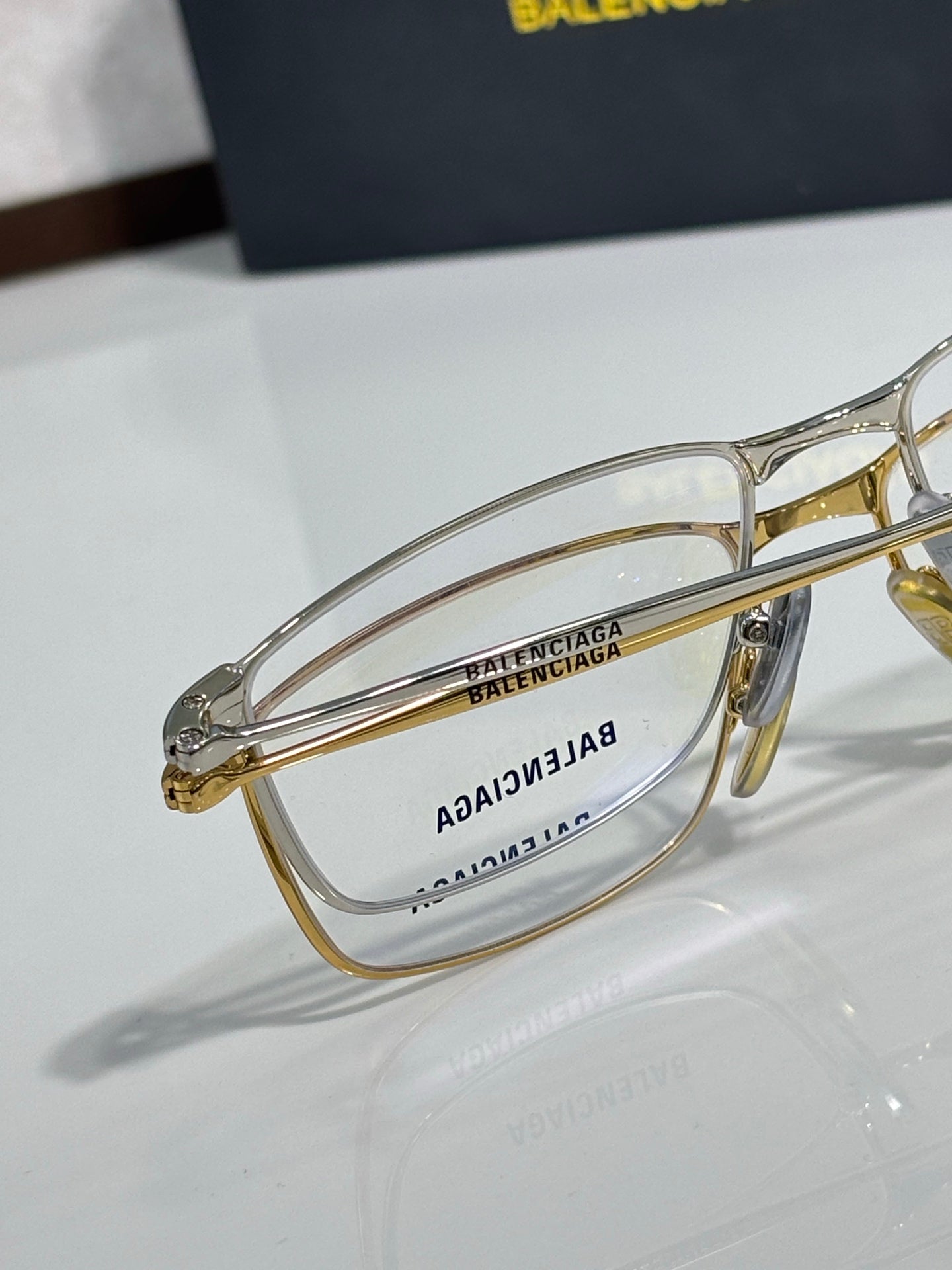 Balenciaga eyeglasses close-up with gold and silver frames and clear lenses.
