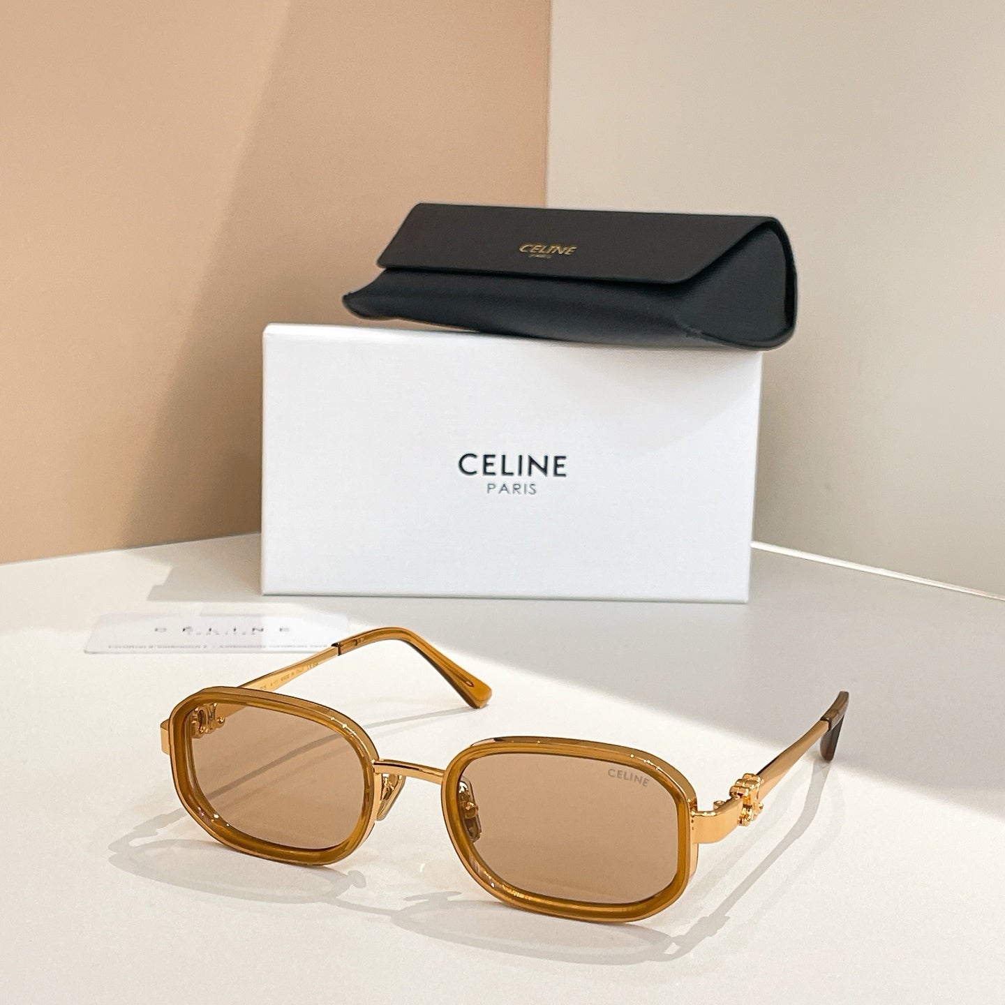 Square sunglasses with light gold frames and tinted brown lenses, temple arms visible