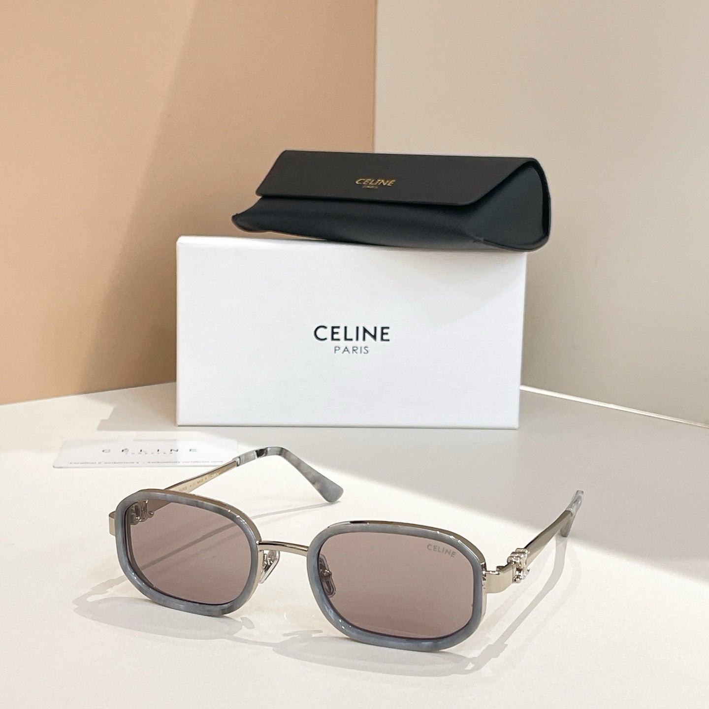 Square sunglasses with dark frames and tinted gray lenses, with temple arms visible