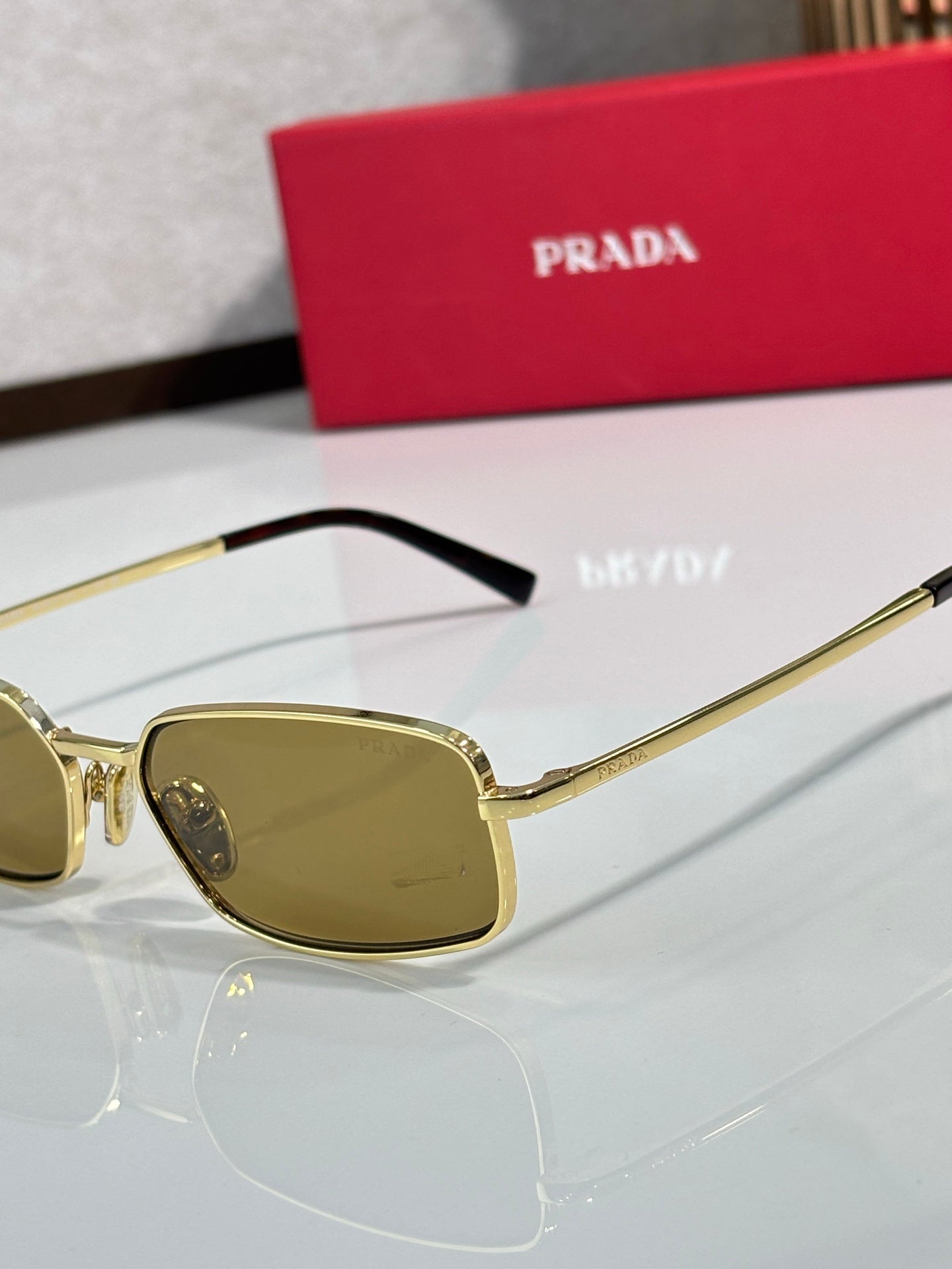 Sunglasses with gold-tone frame and amber lenses, side temple close-up