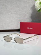 Prada sunglasses with gold frame, tortoise arms, gray tinted oval lenses