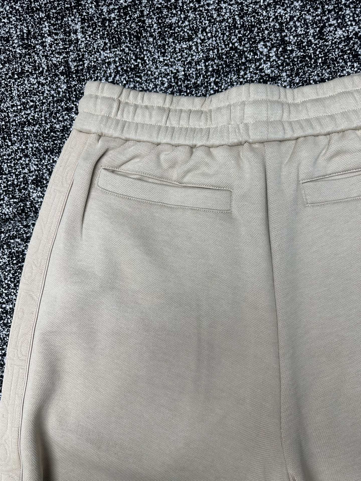 Cream pants close-up of front flap pockets and stitched waistband