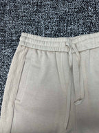 Cream drawstring pants with elastic waistband and flap pocket accents