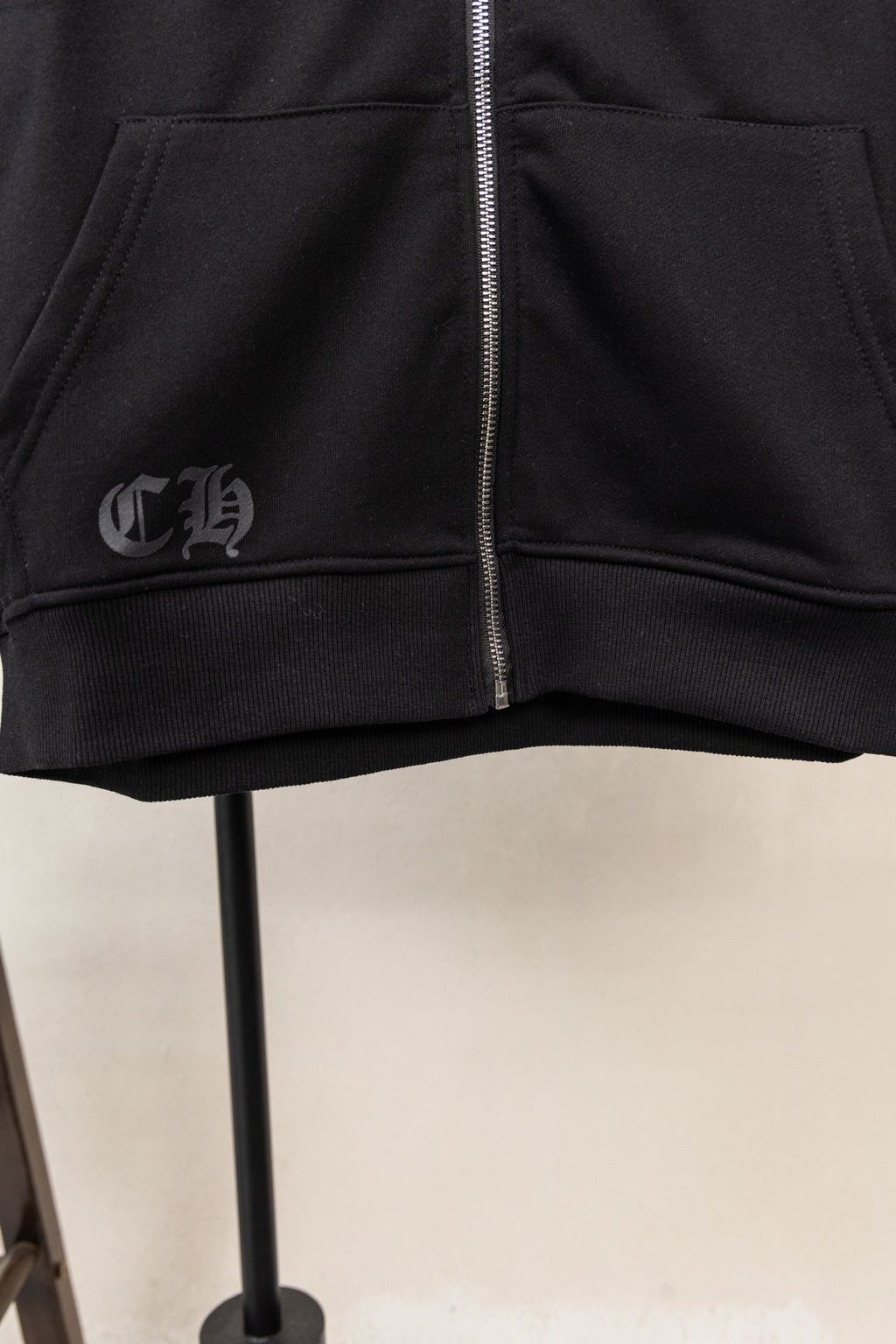 Black zip hoodie front with silver zipper and small chest emblem