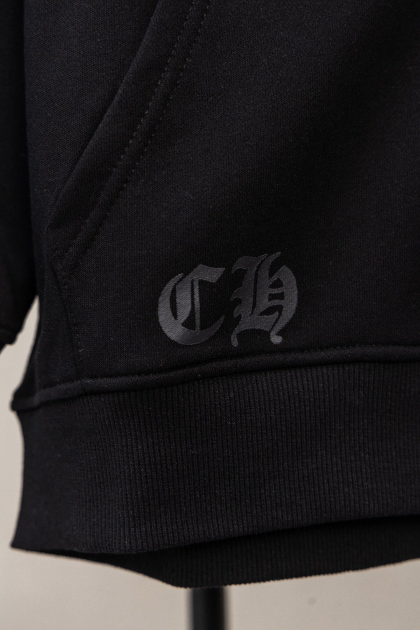 Black zip hoodie with gray logo on sleeve cuff and hem