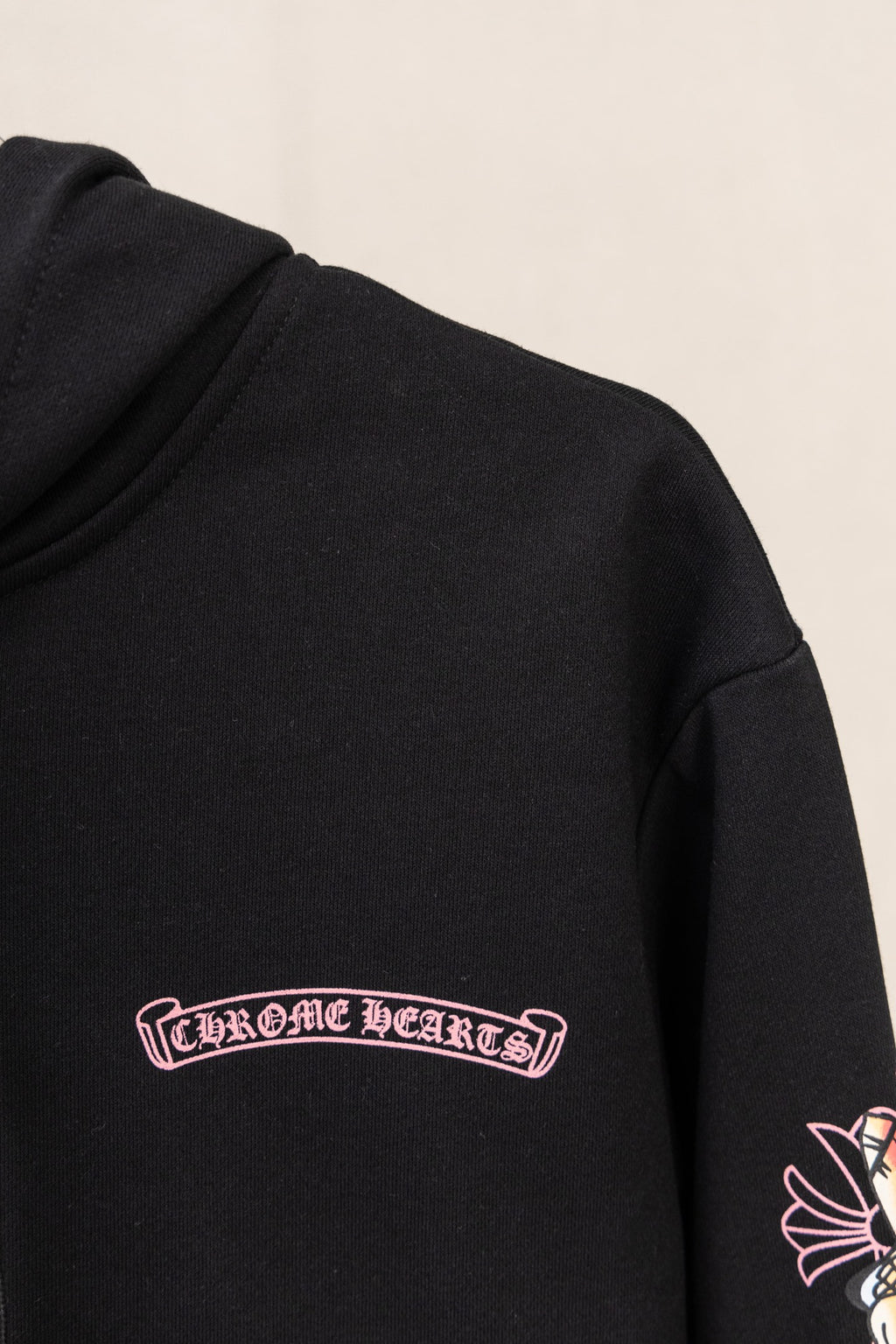 Black hoodie sleeve with red cursive logo graphic near the chest