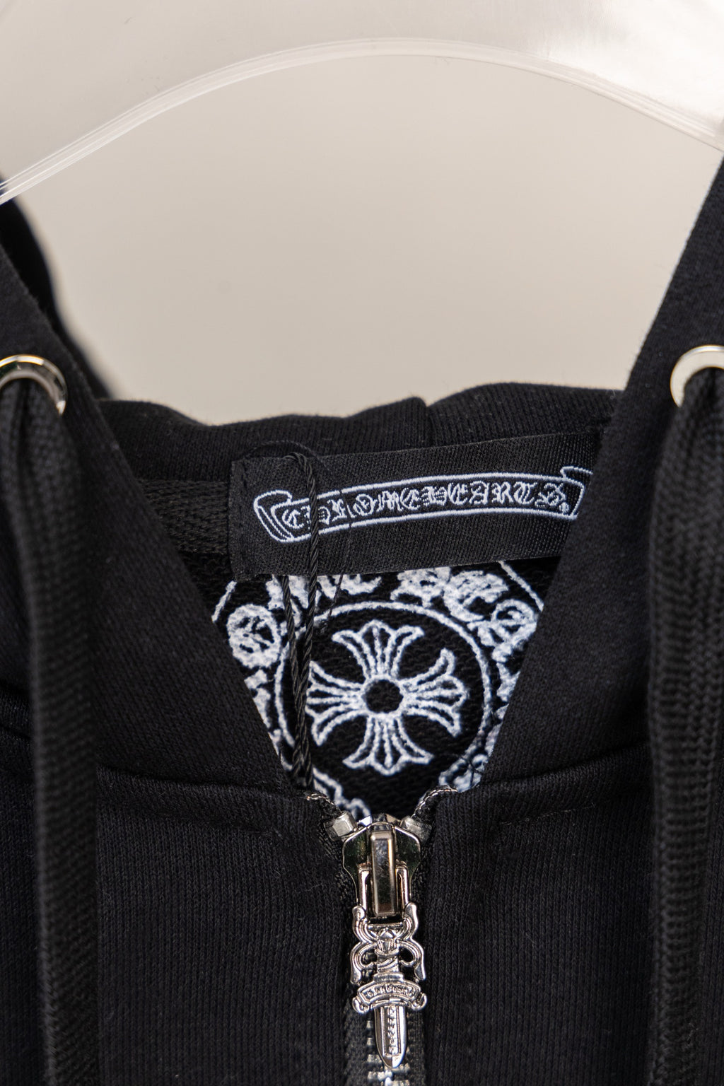 Black hoodie neckline with decorative label and visible silver zipper pull