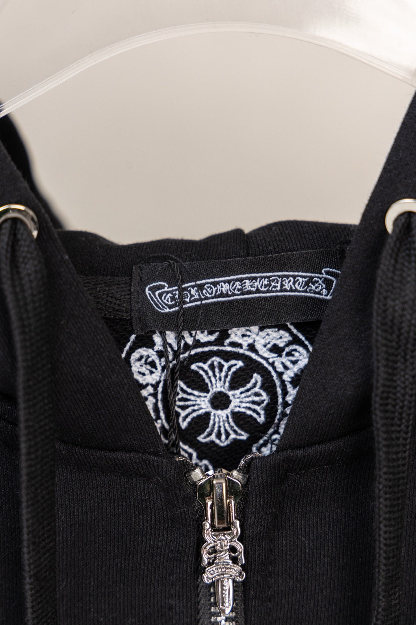 Black hoodie neckline with decorative label and visible silver zipper pull