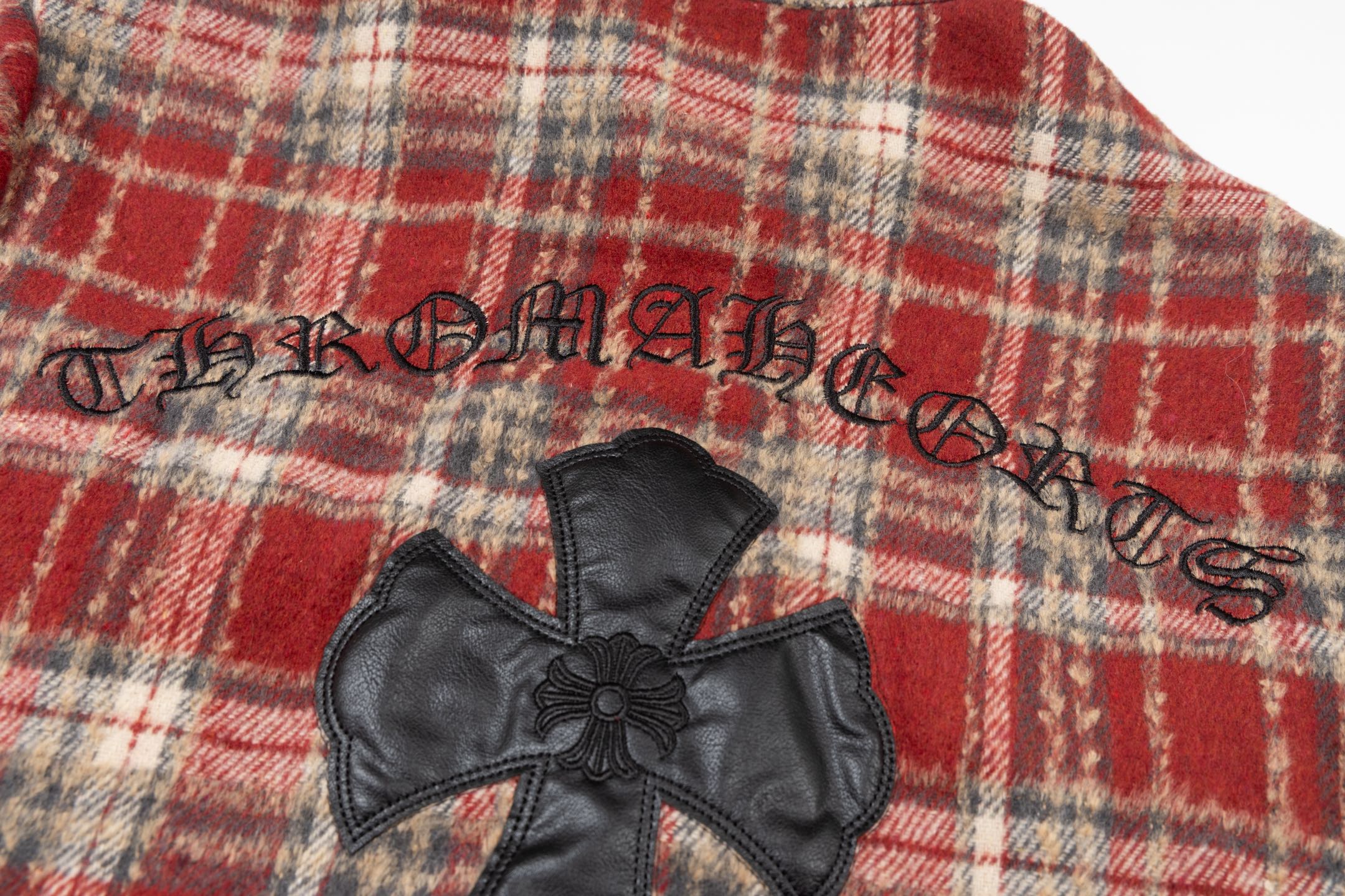 Chrome long clothes small black faux-leather cross with floral center, on plaid fabric
