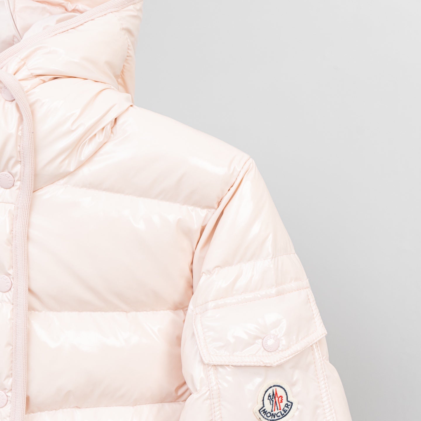 Light pink puffer jacket sleeve with embroidered logo patch