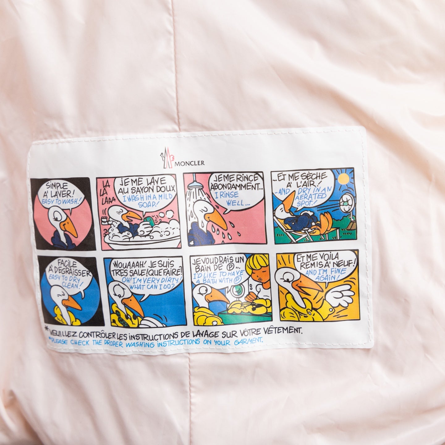 Light pink Moncler puffer jacket front panel with comic-style graphic instructions