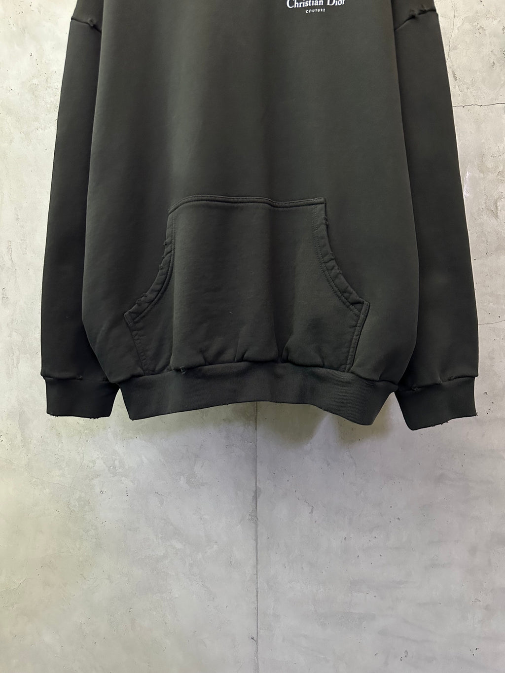 Black Dior hooded sweatshirt with kangaroo pocket detail on front.