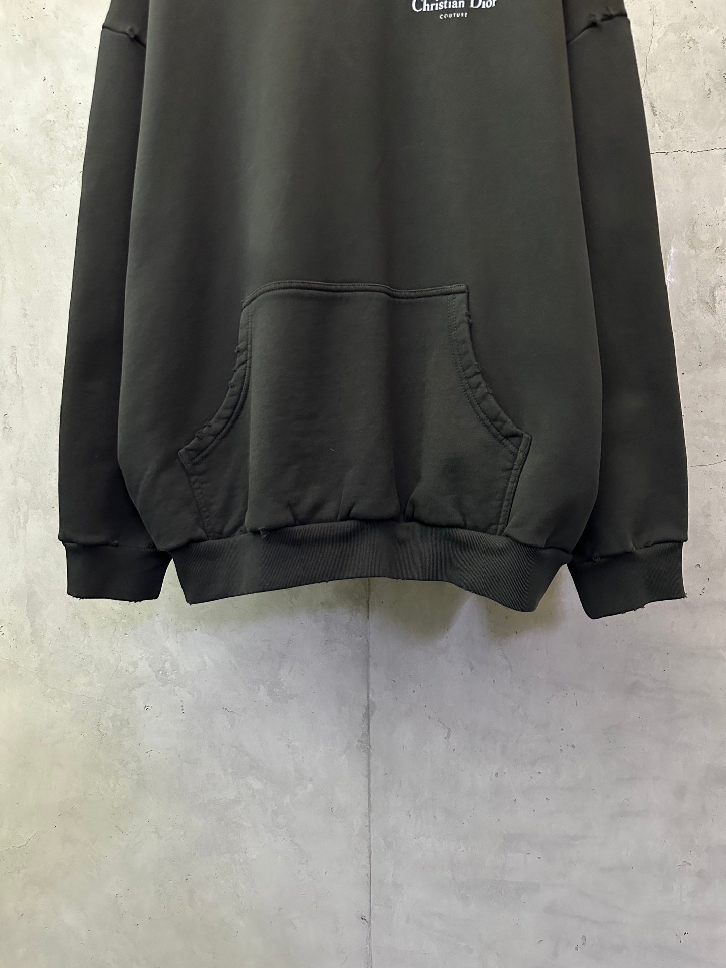 Black Dior hooded sweatshirt with kangaroo pocket detail on front.